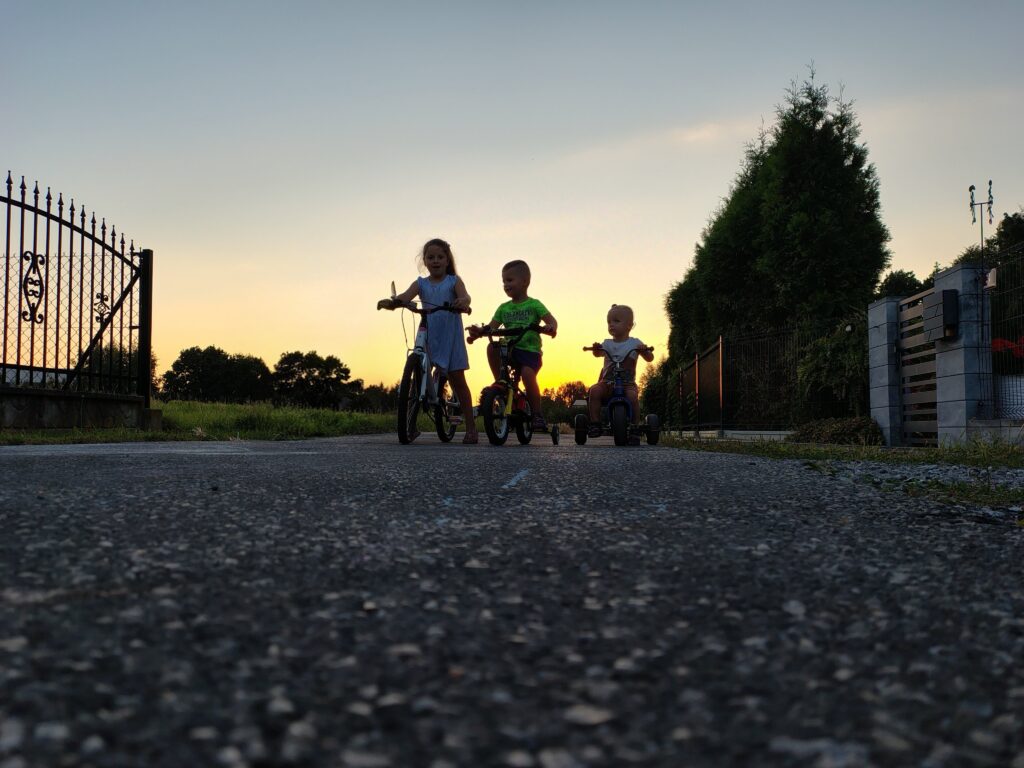 Trójka dzieci na rowerach na tle zachodzącego słońca